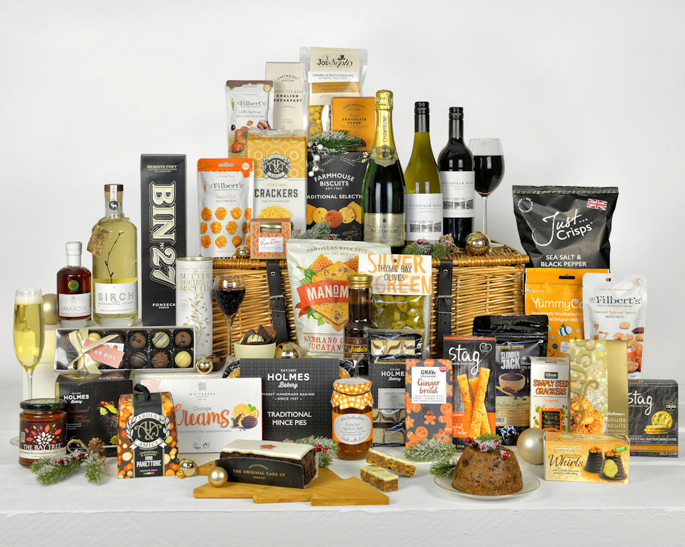 Luxury food and drink including champagne, vodka, wine as well as chocolates, cake, biscuits, snacks, popcorn and tea and coffee in a wicker basket hamper.